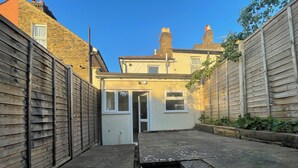 A narrow alleyway with a small house at the end, wooden fences on both sides, and a clear blue sky. - Fullhouse - Croydon centre (Croydon)