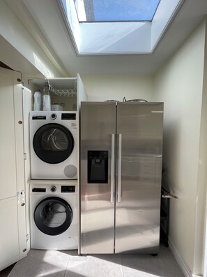 A compact kitchen with a built-in washer and dryer, a stainless steel refrigerator, and a skylight above. - Fullhouse - Croydon centre (Croydon)
