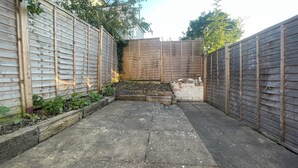 A courtyard with a wooden fence, a stone pathway, and a small garden area with plants. - Fullhouse - Croydon centre (Croydon)