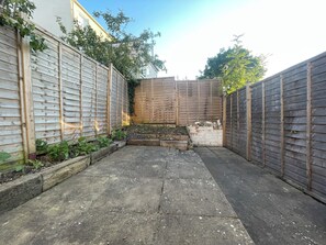 A courtyard with a wooden fence, a stone pathway, and a small garden area with plants. - Fullhouse - Croydon centre (Croydon)
