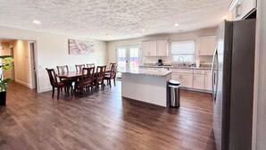 A spacious kitchen with wooden flooring, a central island, and a stainless steel refrigerator.