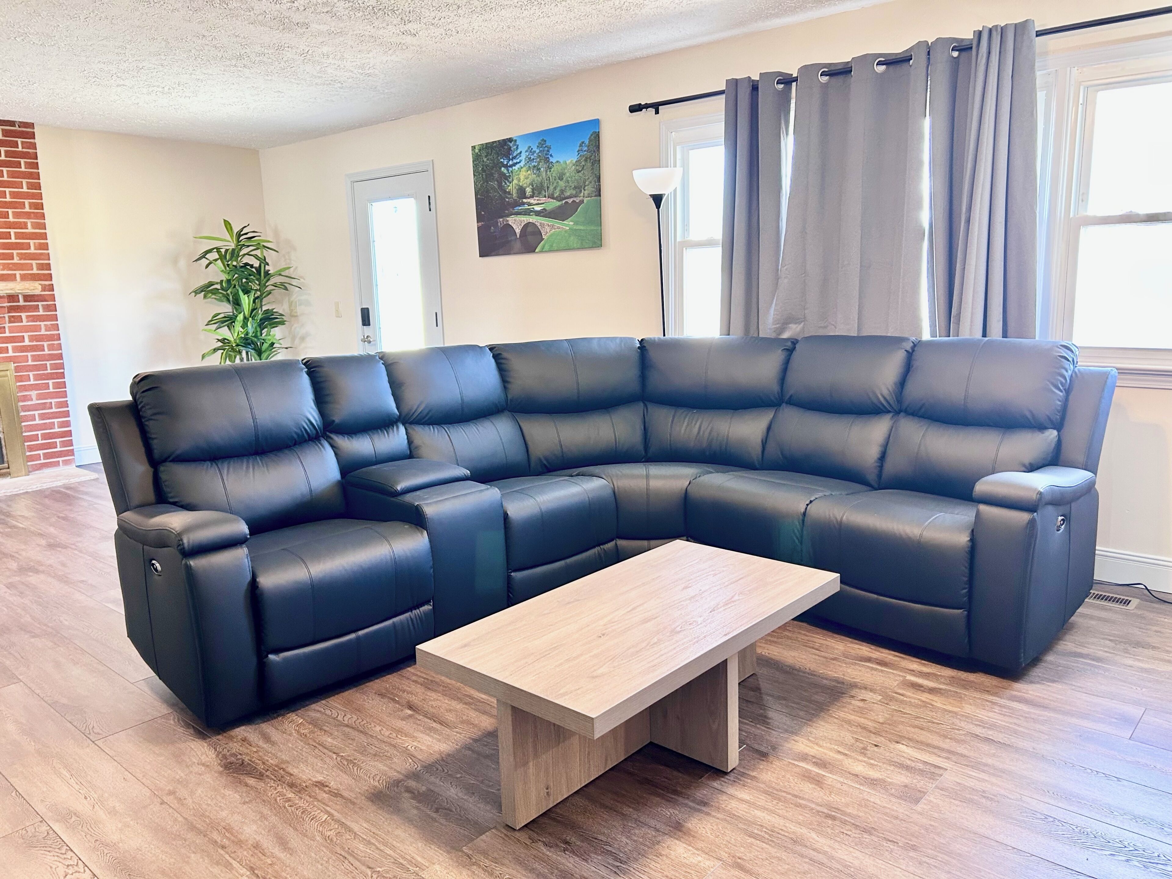 A sectional sofa with a wooden coffee table in a living room with hardwood flooring and a door in the background.