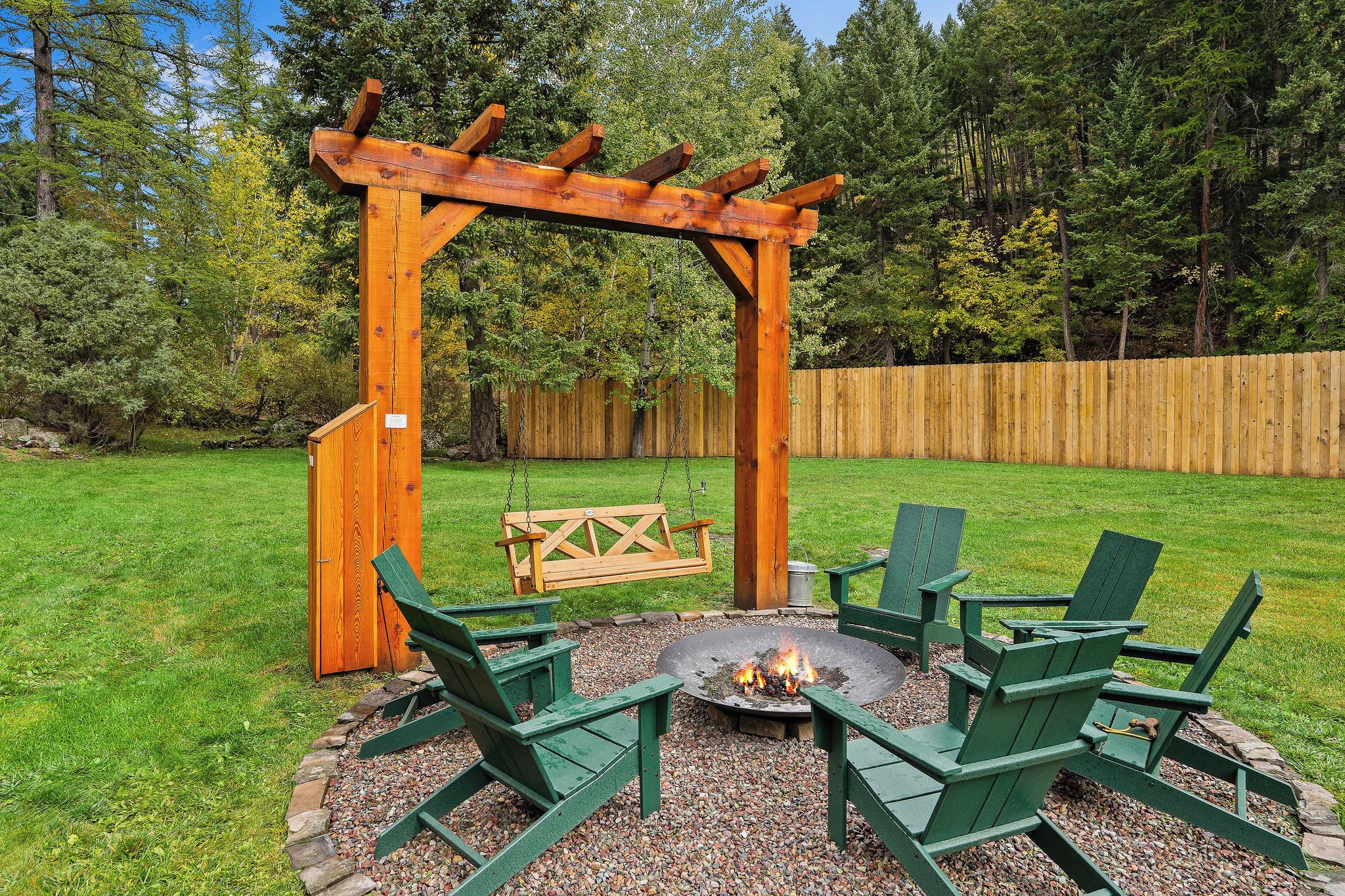 A wooden pergola with a fire pit and seating area.