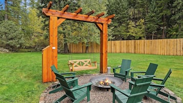 A wooden pergola with a fire pit and seating area.