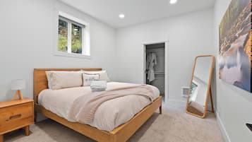 Une chambre à coucher avec un lit en bois, une table de chevet, une fenêtre, une armoire et un miroir.