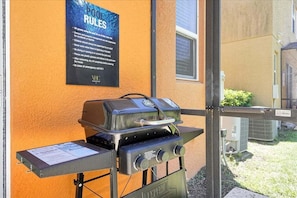 Un barbecue extérieur avec un panneau indiquant les règles à respecter au bord de la piscine.