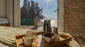 A room with a bed, a tray with cups and a bowl of food, and a view of trees and a body of water through a glass door. - Suite & Relax: The Exclusive Experience of Villa L'Altura (Cala Moresca)