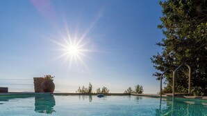 A clear swimming pool with a stone structure and metal ladder on the right. - Suite & Relax: The Exclusive Experience of Villa L'Altura (Cala Moresca)