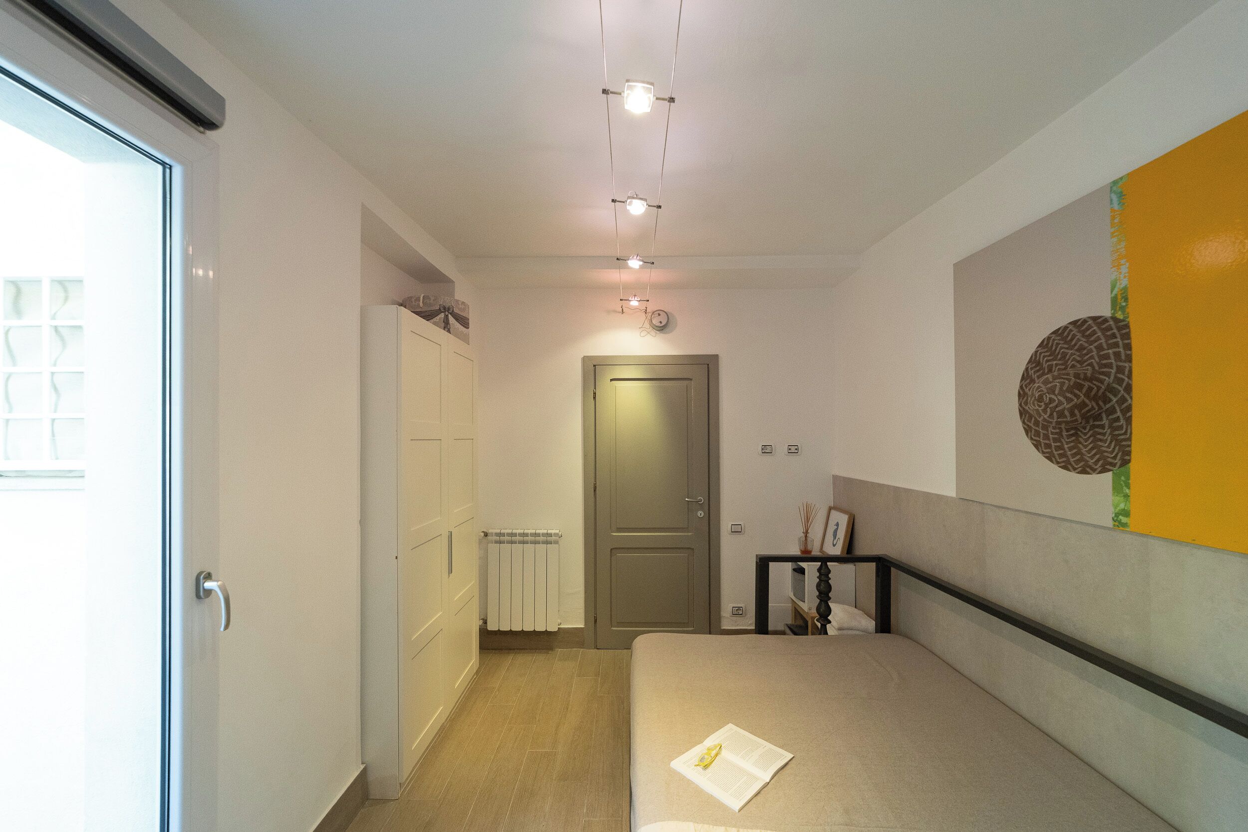 Een slaapkamer met een bed, een deur, een radiator en een muur met een rond ontwerp.