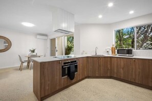 Una cocina moderna con una isla de madera, un microondas y un ventanal con vistas a árboles.