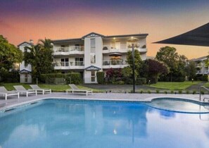 A hotel with a swimming pool, multiple balconies, and a well-maintained garden. - Burleigh Breeze 2‑Bed Beach Walk Retreat (Gold Coast)