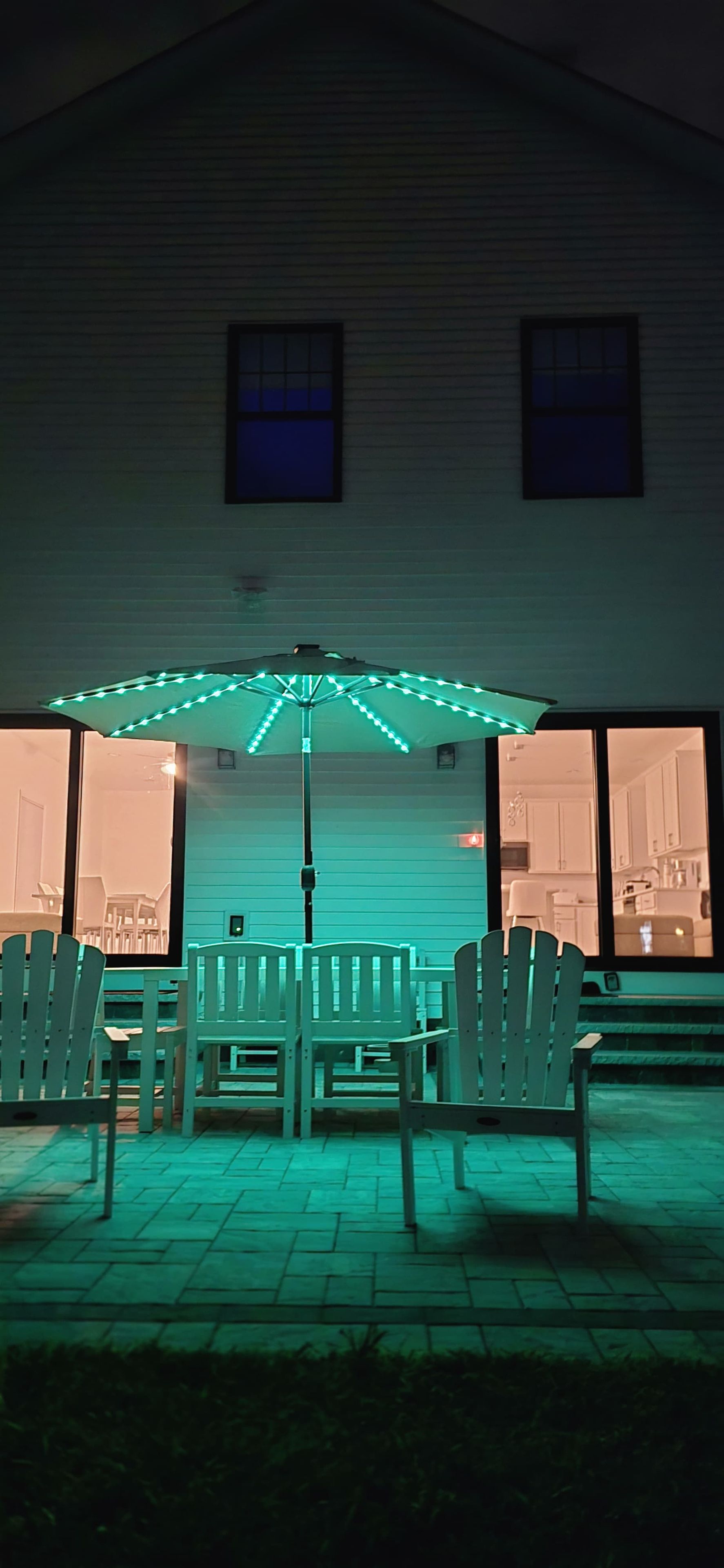 Un espace extérieur aménagé en terrasse, avec une table et des chaises, situé sous une tonnelle décorée de guirlandes lumineuses.