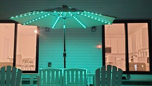 An outdoor patio area with a table and chairs under a canopy with string lights. - Spacious 4-bedroom lake house in Shrewsbury MA.   (Shrewsbury)
