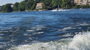A body of water with waves, a jet ski in motion, and buildings in the background.