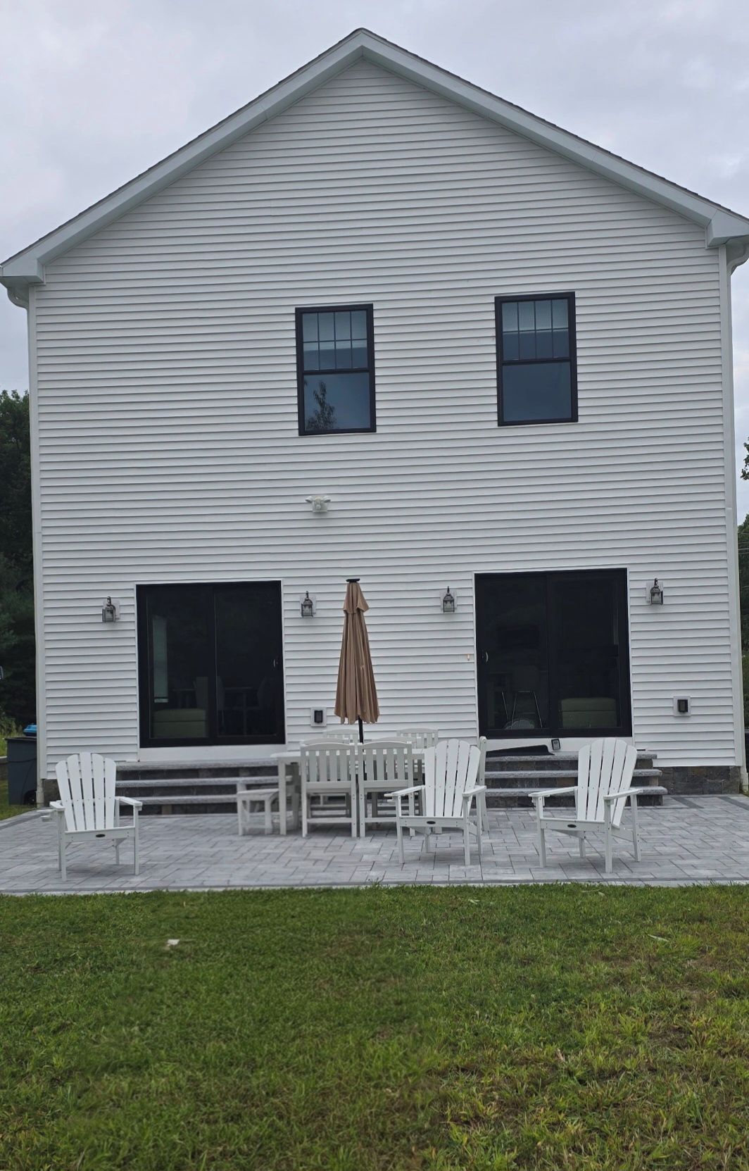 A two-story building with a covered patio area featuring outdoor furniture and a brown umbrella.