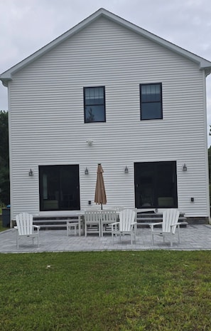 A two-story building with a covered patio area featuring outdoor furniture and a brown umbrella.