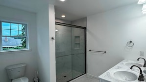 A bathroom with a toilet, a shower enclosure, and a sink.