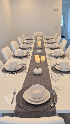 A long dining table set for a meal with white chairs, centered with candles and pumpkins. - Spacious 4-bedroom lake house in Shrewsbury MA.   (Shrewsbury)