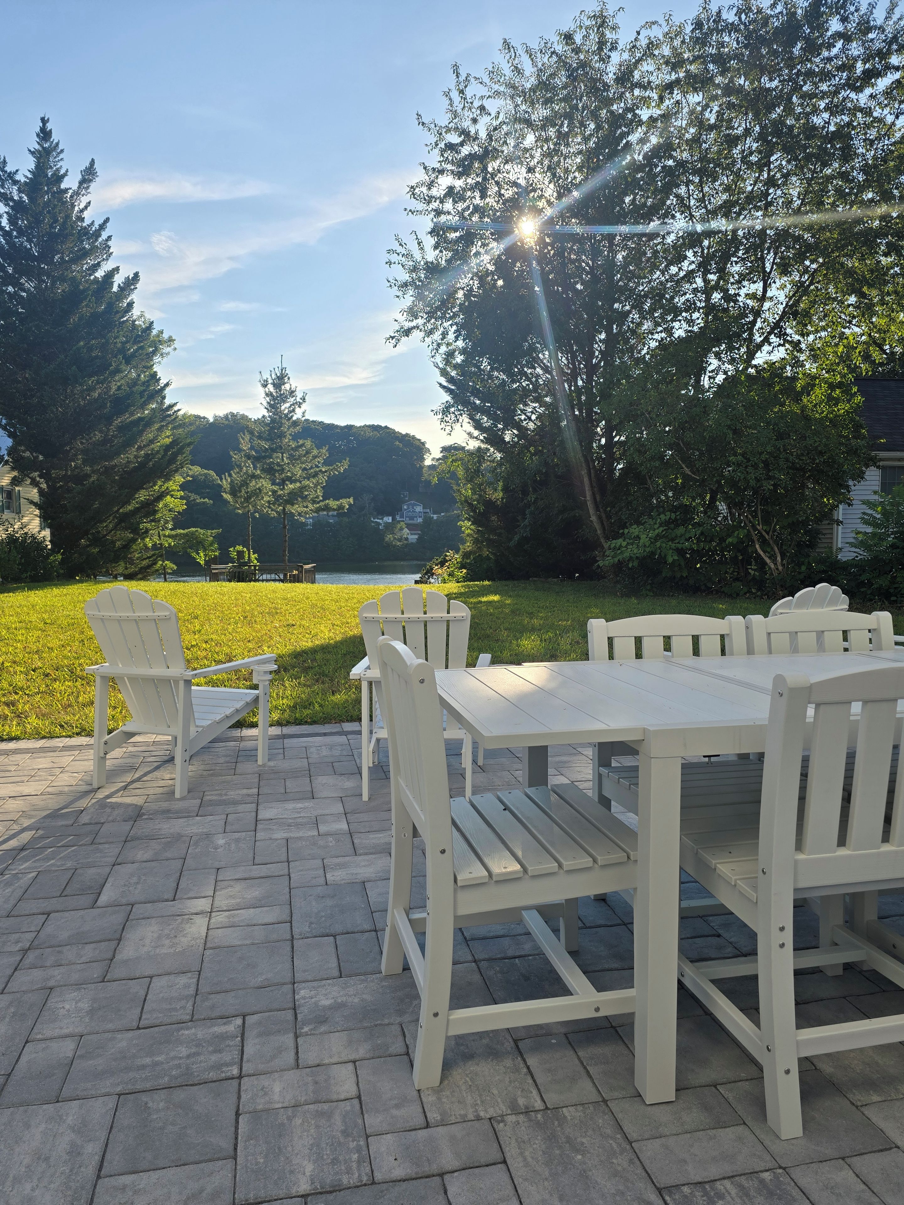 An outdoor patio with a table and chairs, a grassy area, and trees.