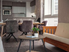 Ein modernes Wohnzimmer mit einer Couch, zwei Sesseln, einem Couchtisch und einer Topfpflanze.