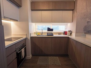 Eine moderne Küche mit Holzausstattung, einem eingebauten Backofen und einem Fenster über der Spüle.