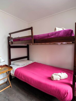 Een stapelbed met een onderbed en een eenpersoonsbed, beide met roze beddengoed.