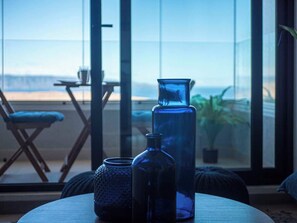 A room with a large window, a table with decorative glass bottles, and a chair. - Costa Home - Departamento Vista Valparaíso (Concón)