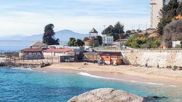 A coastal town with a beach, a small building labeled 'Restaurante Llenes,' and a stone wall.