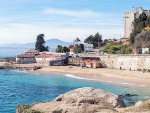 Eine Küstenstadt mit Strand, einem Restaurant namens 'Restaurante Llenes' und einer Steinmauer entlang der Küste.