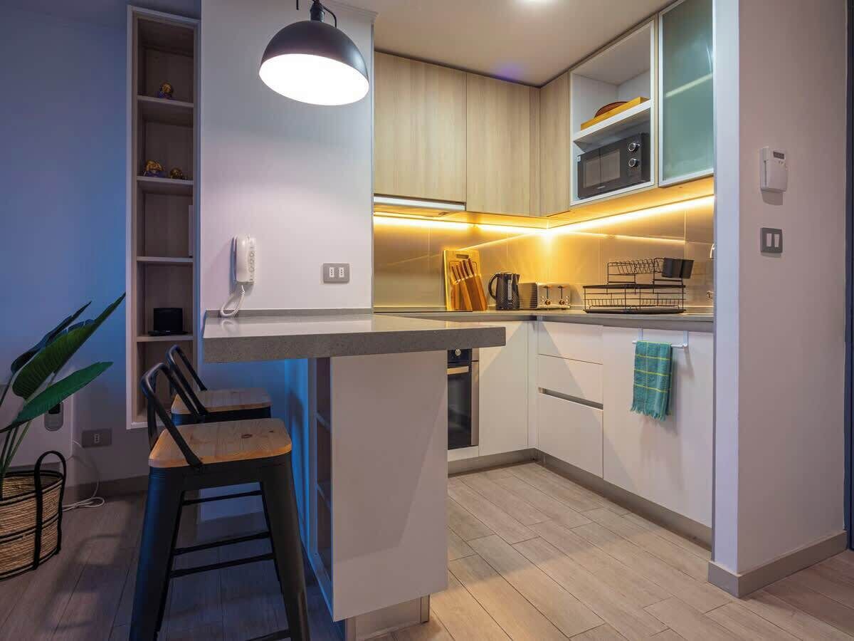A modern kitchen with a central island, built-in appliances, and a pendant light.