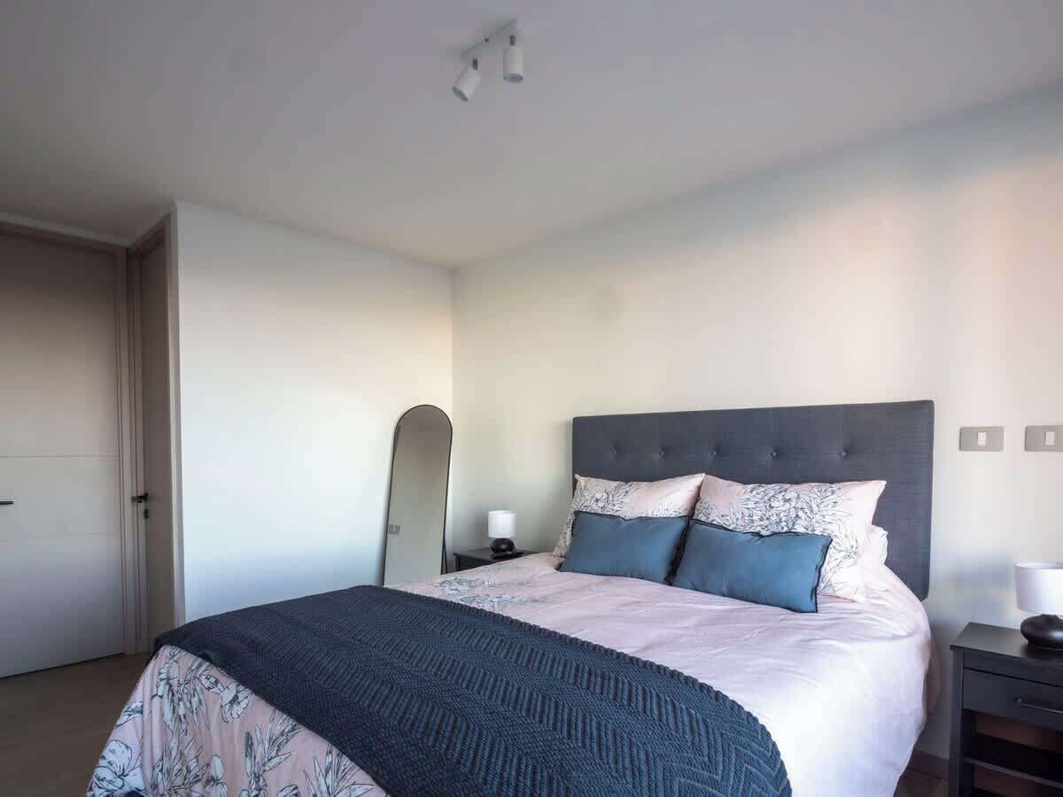 Een hotelkamer met een bed, nachtkastje en een spiegel.