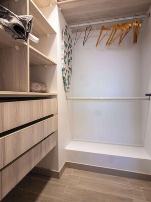 Un closet amplio con estantes de madera, una barra para colgar con perchas de madera y un perchero con diseño.