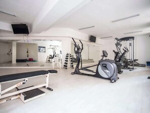 A gym with exercise equipment, a bench, and a mirrored wall. - Oceanfront Luxury Apt w/ 8 PAX , Pool & Gym (Viña del Mar)