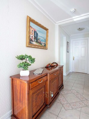 Un pasillo con un armario de madera, un cuadro enmarcado y una planta en maceta.