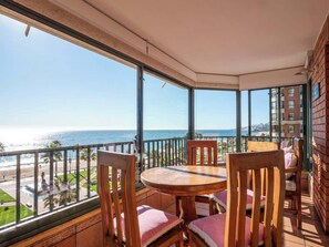 A balcony with a table and chairs, overlooking a beach and ocean. - Oceanfront Luxury Apt w/ 8 PAX , Pool & Gym (Viña del Mar)