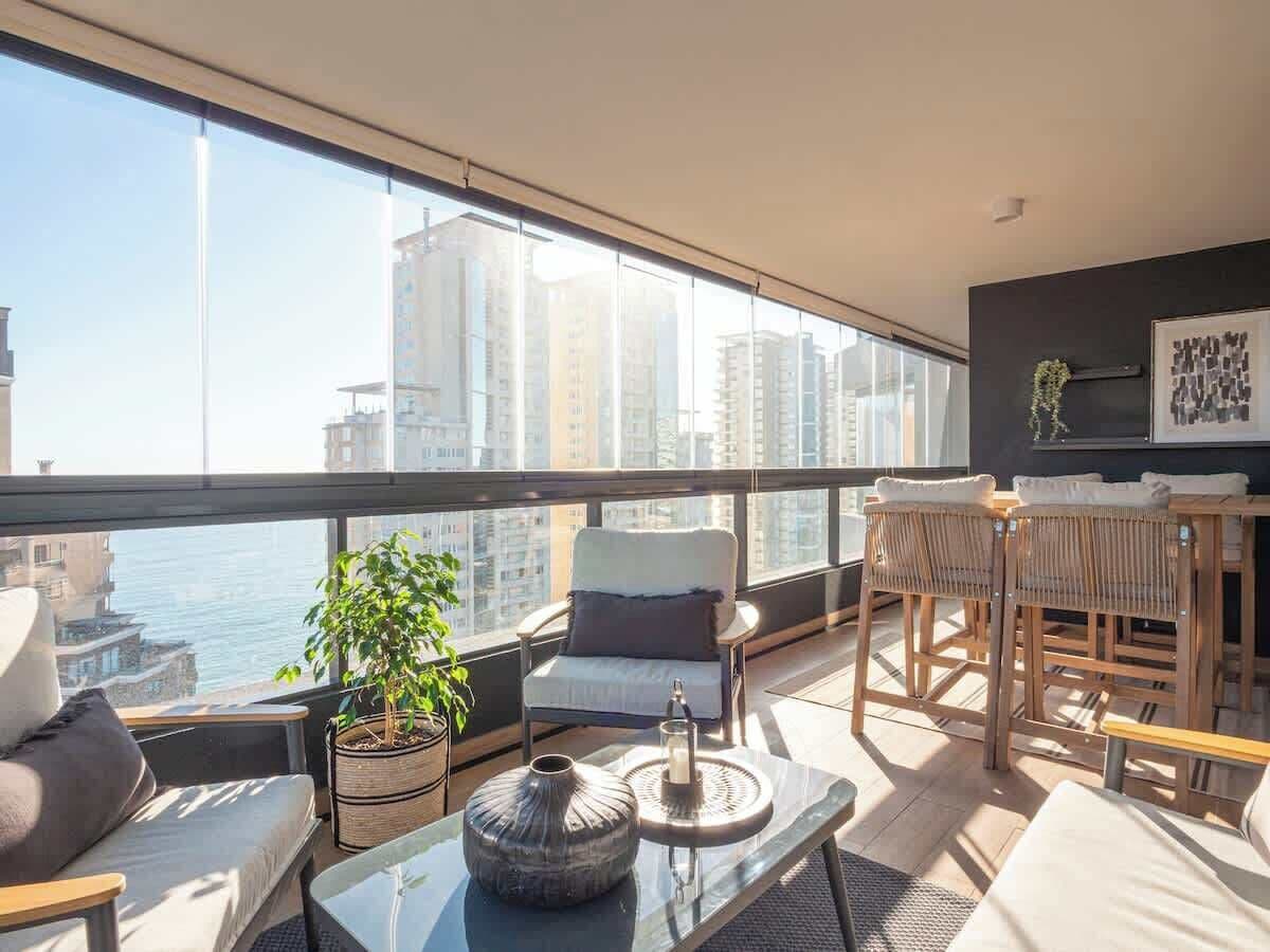 Un balcon moderne avec un canapé, une chaise, une table à manger et une plante en pot.