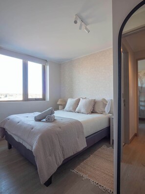 A bedroom with a bed, a bedside table, a lamp, a window, and a door. - Costa Home 7 PAX - Lujoso - WIFI 1000 MBPS HS (Concón)