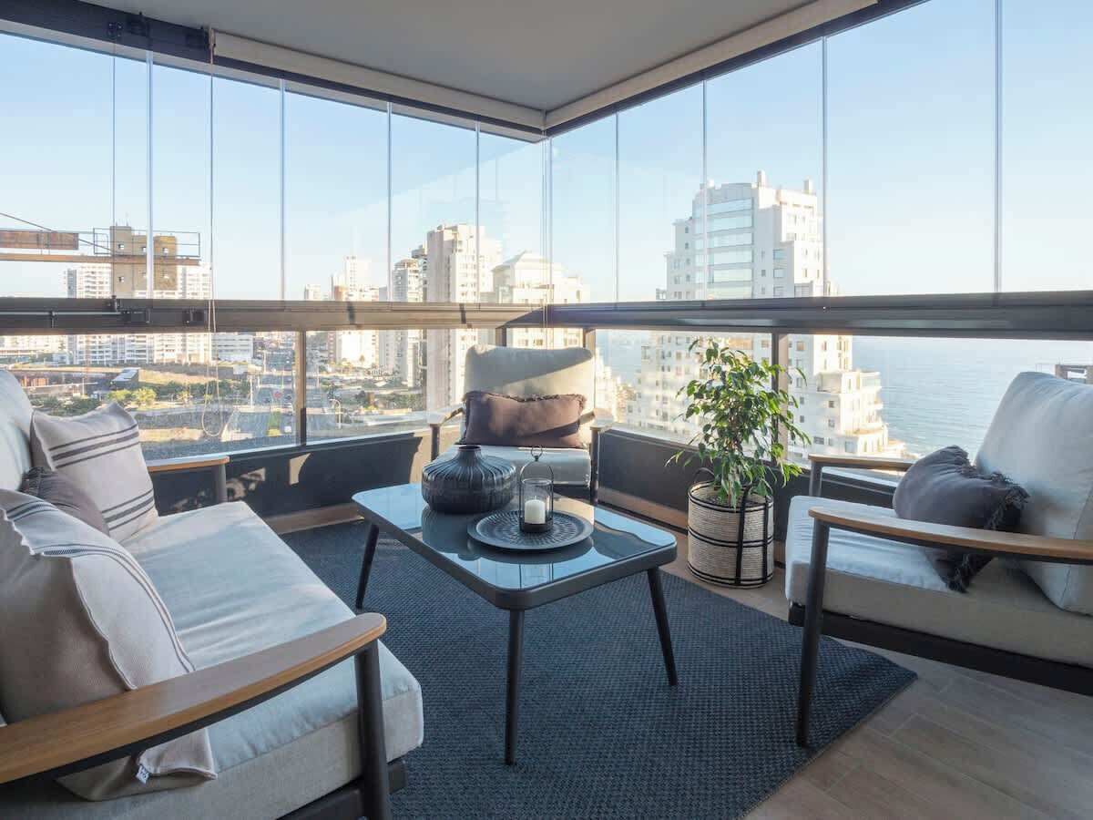 Un salon moderne avec une table en verre, deux canapés et une vue sur le paysage urbain.