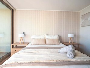 Une chambre d’hôtel avec un grand lit, deux tables de chevet avec des lampes et une fenêtre.