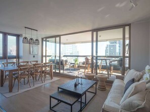 A spacious living area with a dining set, a sofa, and a balcony with a view of the city. - Costa Home 7 PAX - Lujoso - WIFI 1000 MBPS HS (Concón)