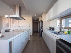 Une cuisine moderne dotée d’un îlot central, d’appareils électroménagers en acier inoxydable et d’un long plan de travail.