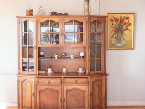 A wooden cabinet with glass doors, shelves, and drawers, containing various decorative items.