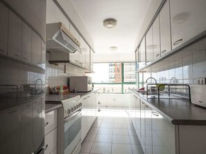 A modern kitchen with white cabinets, a built-in oven, and a window overlooking a cityscape.