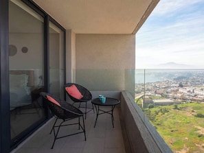 A balcony with two chairs and a table, overlooking a cityscape. - Costa Home - 2P Vistas Mauco (Concón)