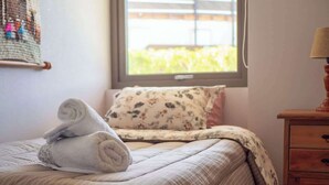 Uma cama bem arrumada com um cobreleito listrado e um travesseiro estampado com motivos florais.