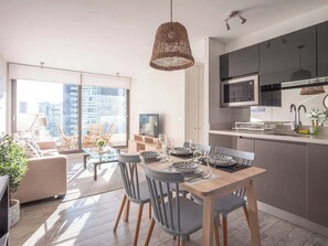 Un appartement moderne comprenant un coin repas, une cuisine et une grande fenêtre donnant sur la ville.