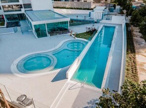 A modern pool area with a long rectangular pool, a smaller circular pool, and a covered seating area. - Costa Home 4 PAX Edificio Wave WIFI (Concón)