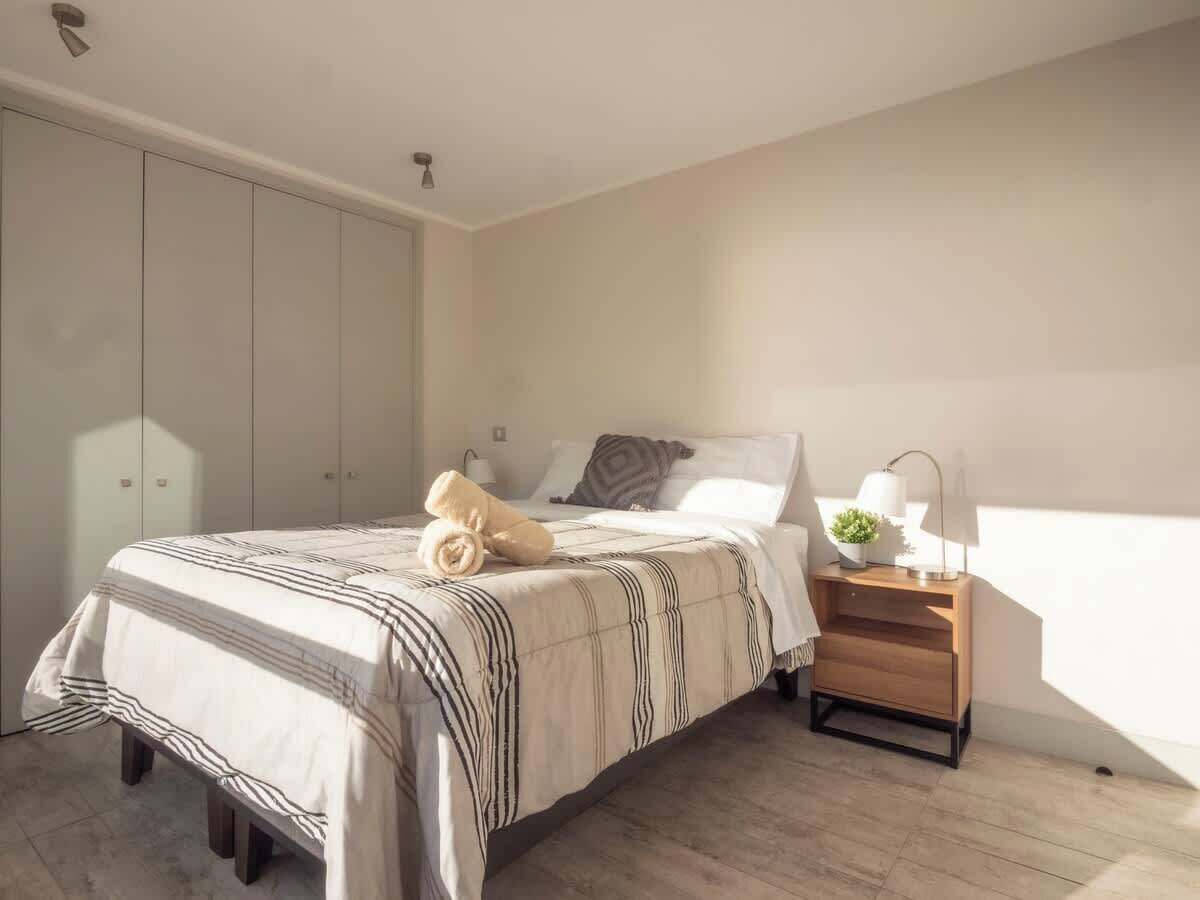 Une chambre à coucher avec un lit, une table de chevet, une lampe et une armoire.