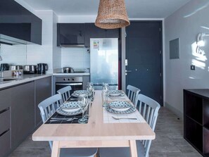Een moderne keuken met een eettafel voor vier personen, voorzien van roestvrijstalen apparatuur en een grote koelkast.