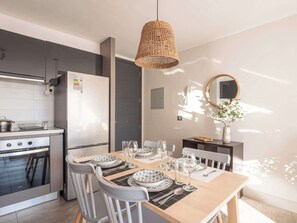 A modern kitchen with a dining area, equipped with a stove, oven, and refrigerator. - Costa Home 4 PAX Edificio Wave WIFI (Concón)
